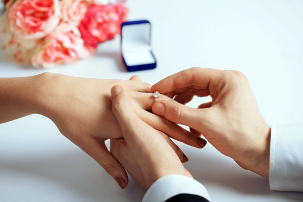 Noivo colocando anel de noivado na mão da noiva